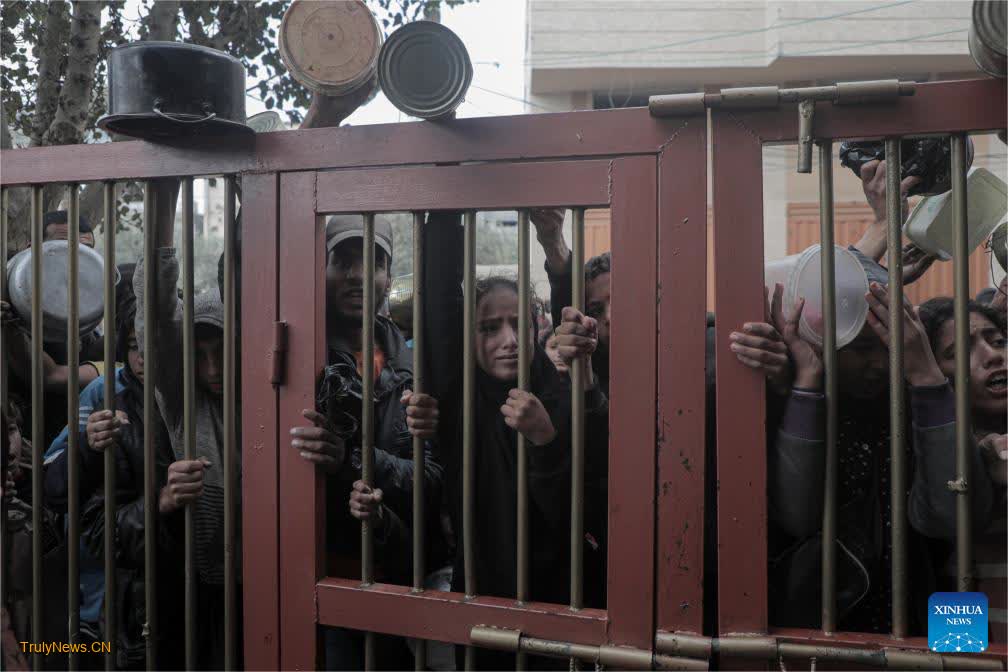 People receive food relief at food distribution center in city of Deir al-Balah, central Gaza Strip